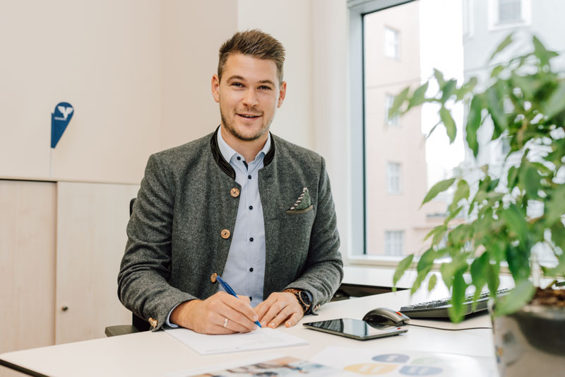Mitarbeiter sitzt am Schreibtisch und lacht